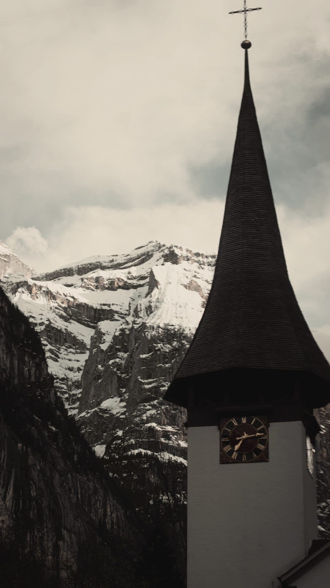 A church steeple beneath snow-covered peaks in the Swiss Alps