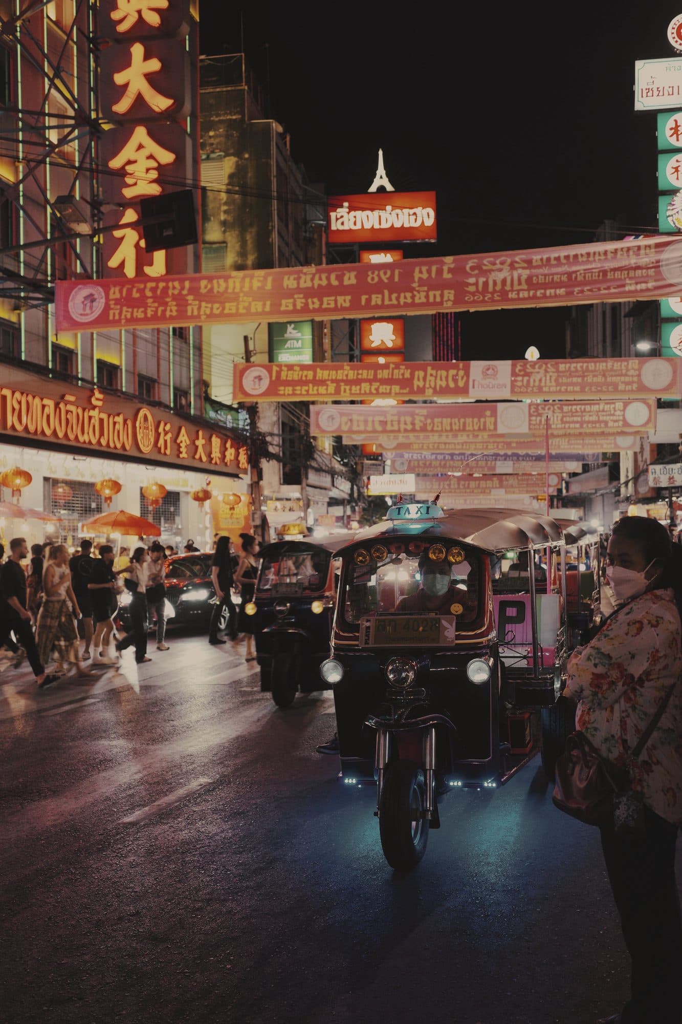 A tuk-tuk under neon signs on Yaowarat Road in Bangkok's Chinatown at night