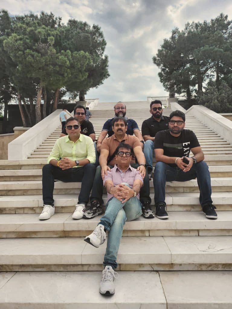 A group of friends on stone steps under pine trees