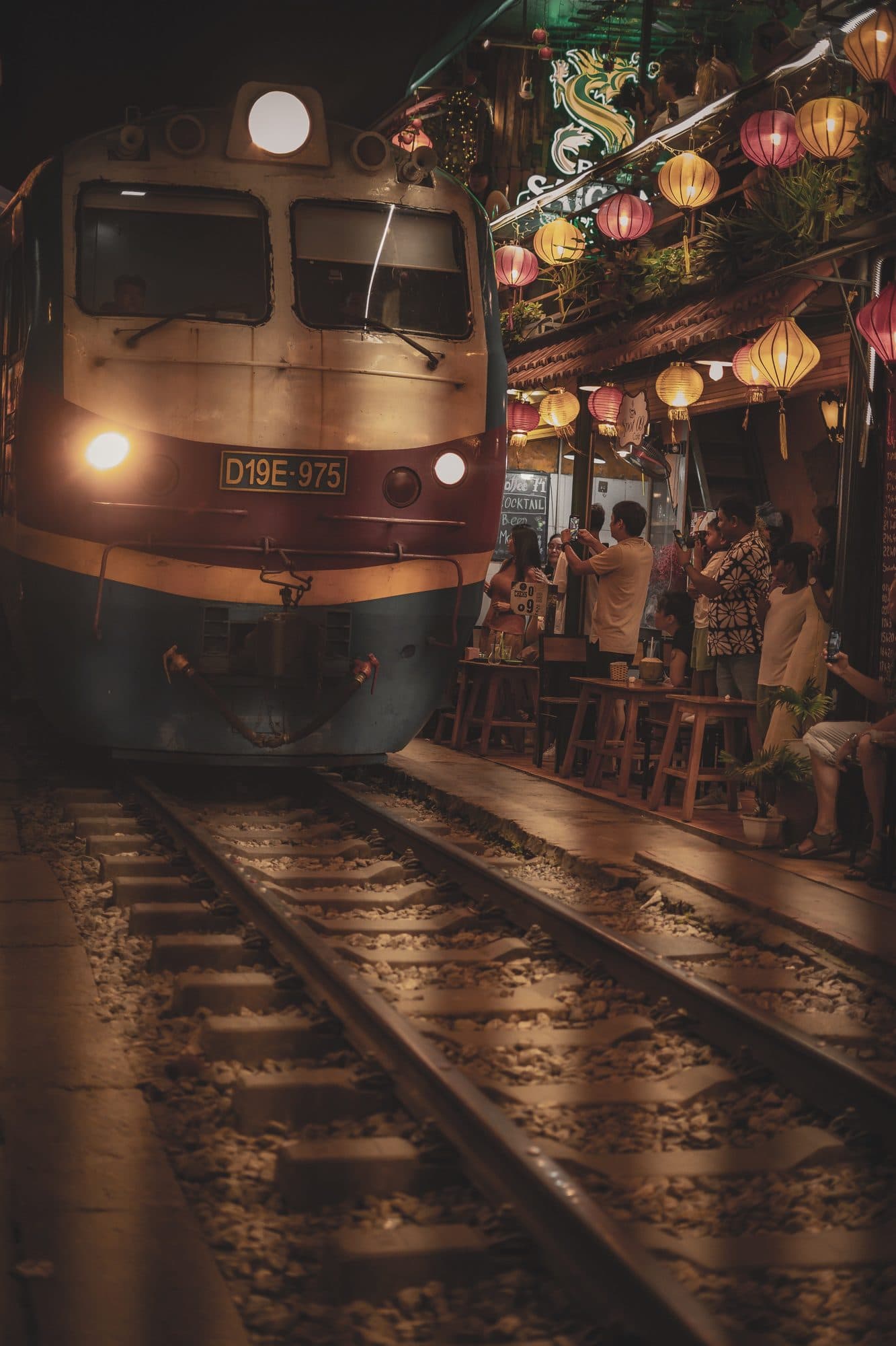 A train edging through Hanoi's lantern-lit train street at night