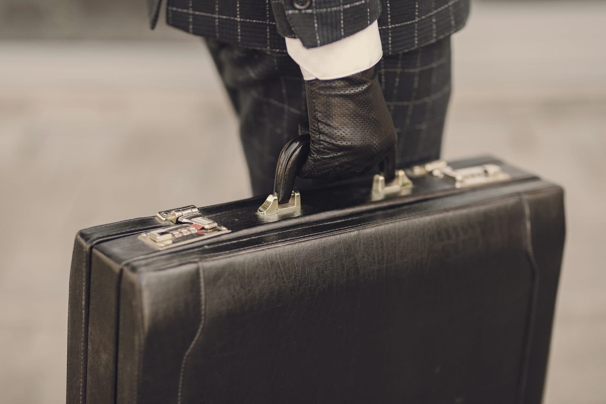 A gloved hand carrying a leather briefcase