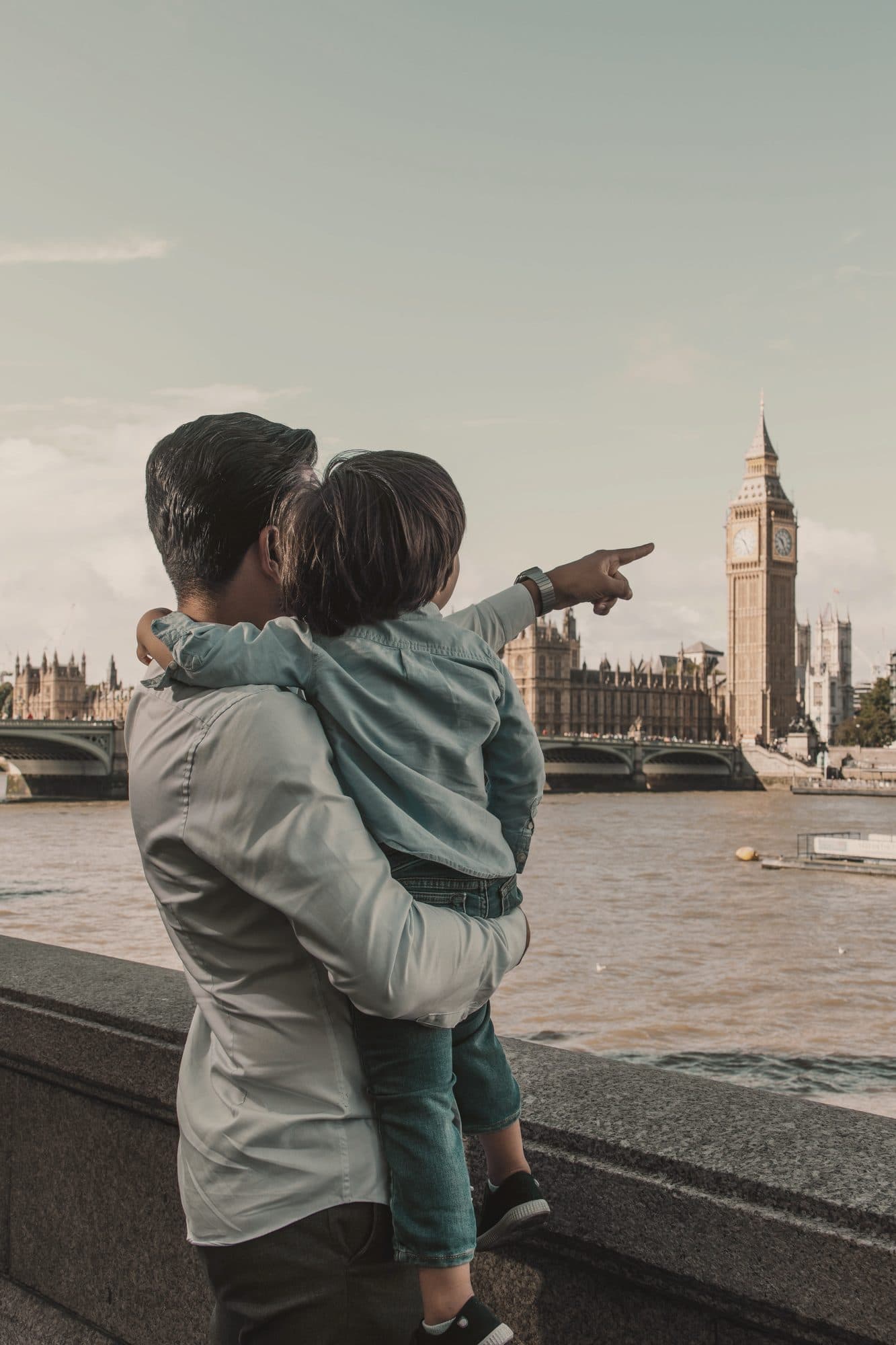 A father holds his son as he points at Big Ben across the Thames in London