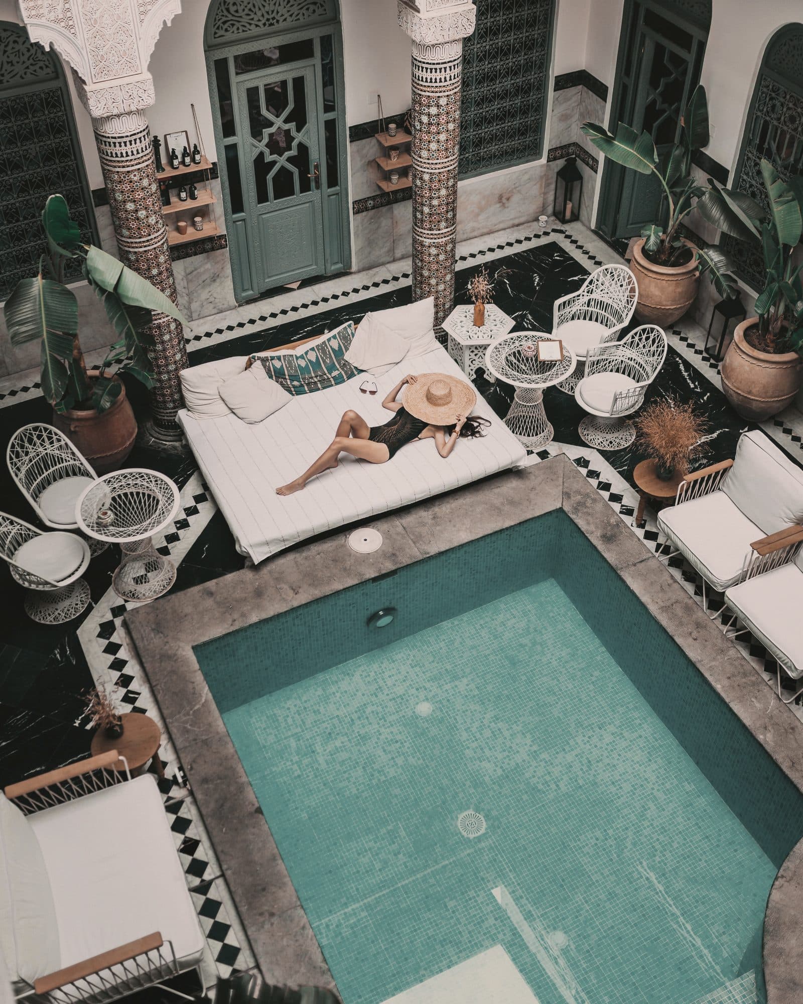 A traveller resting beside the pool in a tiled riad courtyard