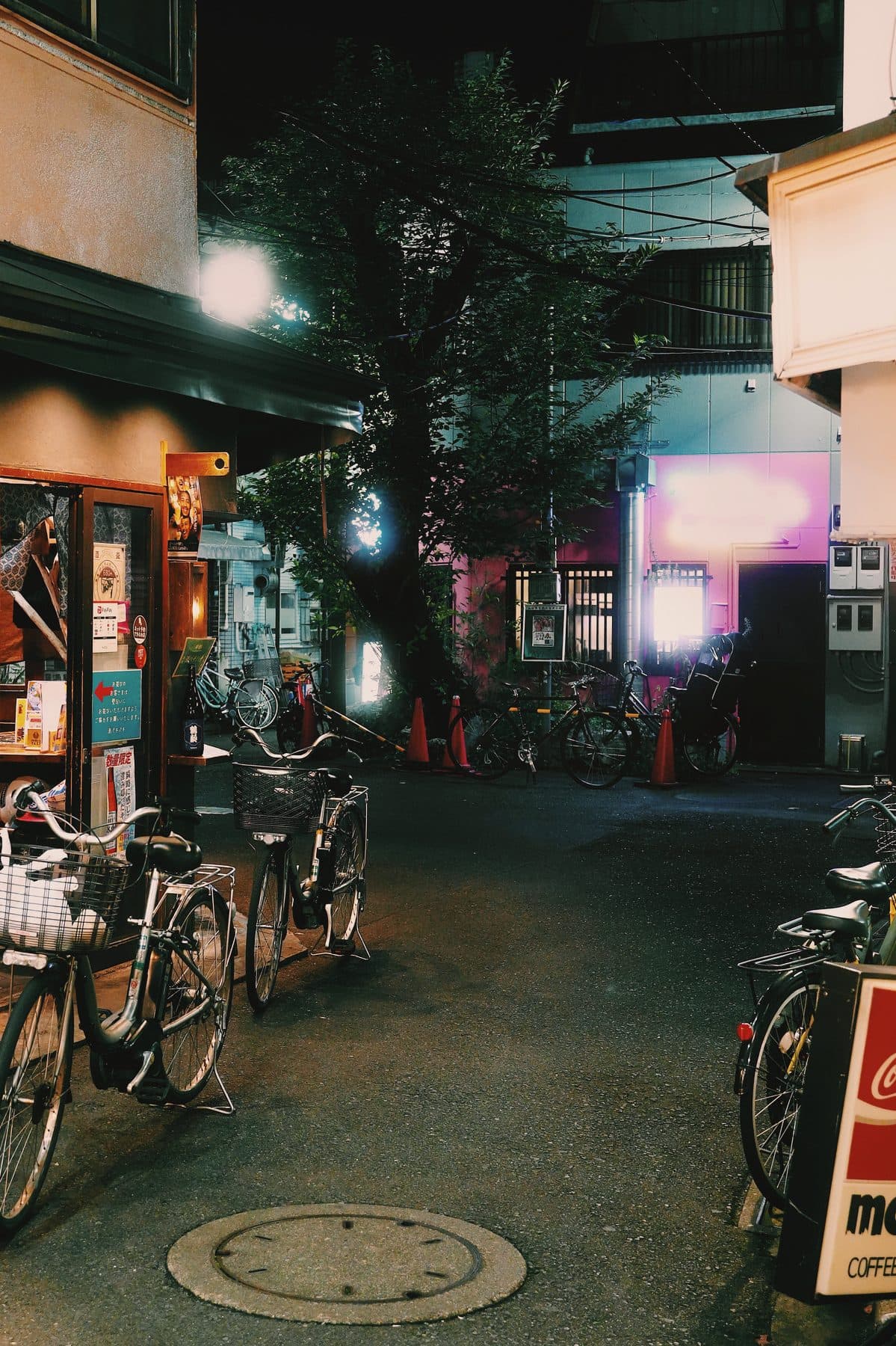 A quiet Tokyo back street at night with bicycles parked outside a small bar